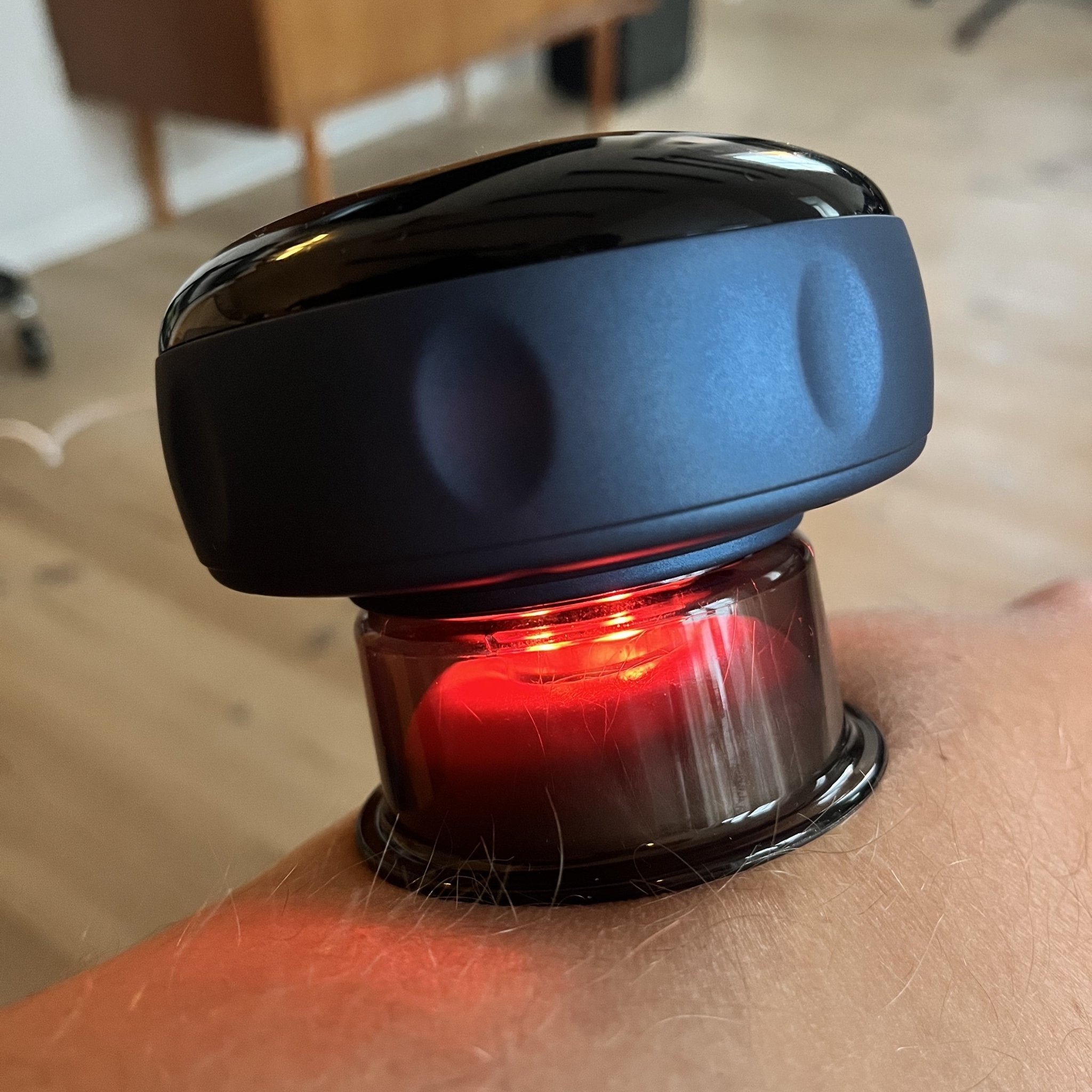 Et nærbillede af en Purely Nordic Smart Cup Basic spændt om et håndled, med et lysende rødt lys på den nederste halvdel, 