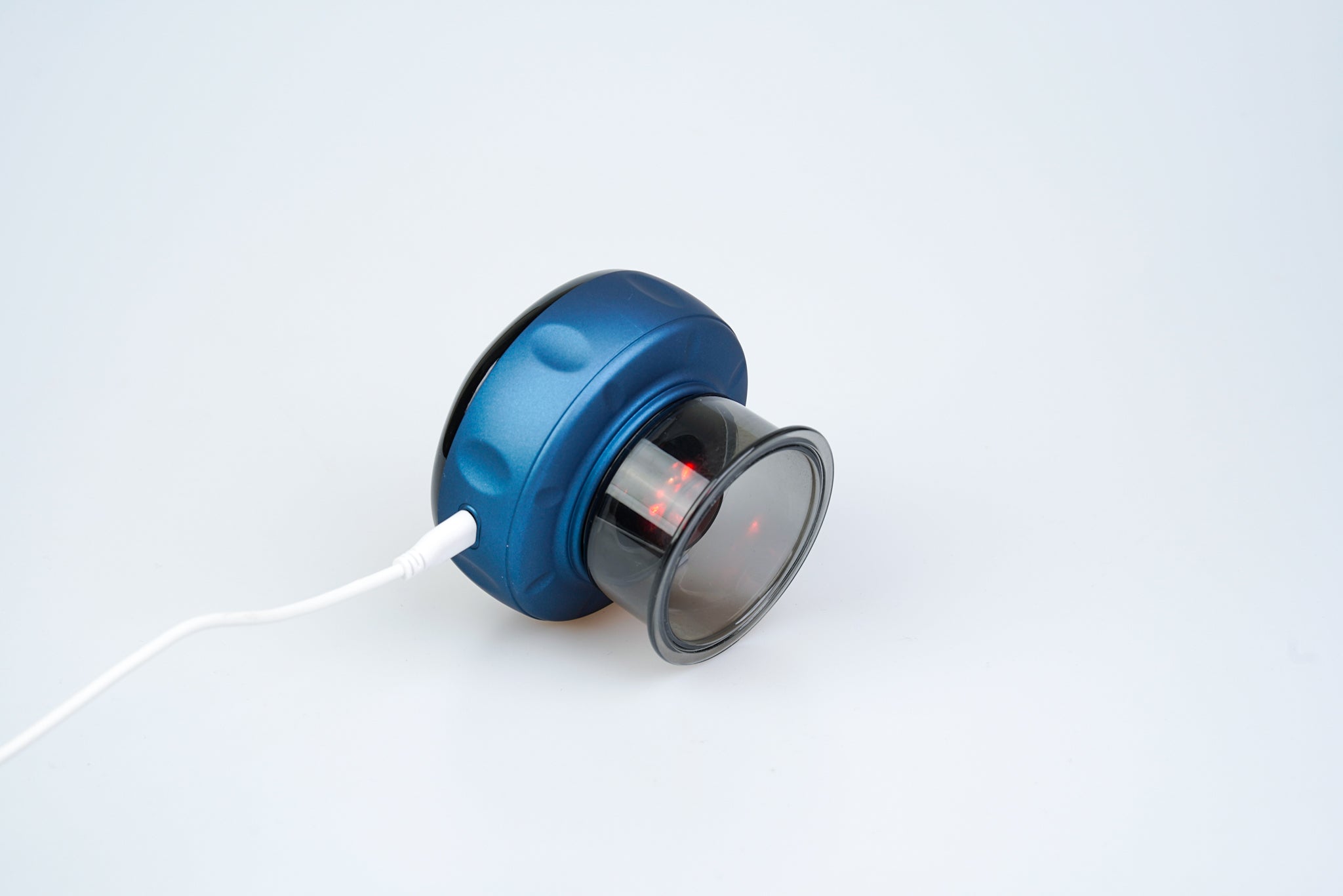 En blå hovedtelefon med åben ryg, der ligger på siden med et hvidt lydkabel påsat, vist mod en almindelig hvid baggrund. Det synlige højttalerelement er synligt gennem den rent nordiske klare yderkappe.